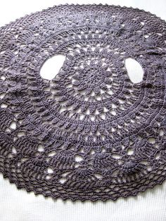 a crocheted doily with holes in the middle on a white table cloth