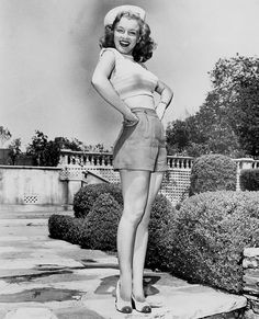 an old black and white photo of a woman in short skirt with her hands on her hips