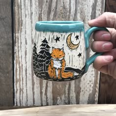 a hand holding a coffee mug with a fox on it