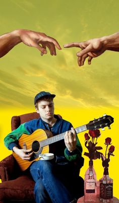 a man sitting on top of a couch holding a guitar in front of two other hands