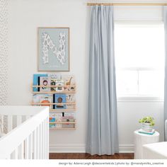 a baby's room with white walls and blue curtains