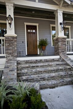 a car parked in front of a gray house with white trim and stone steps leading up to the front door