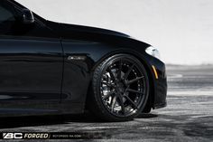 the front end of a black car parked in a parking lot with no one around it