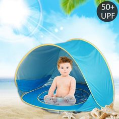 a baby sitting in a blue tent on the beach