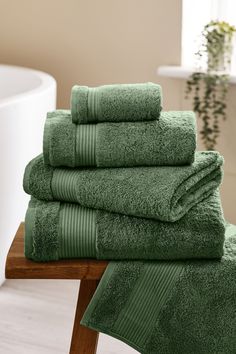 a stack of green towels sitting on top of a wooden table