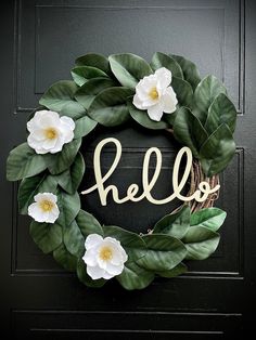 a wreath with the word hello painted on it and white flowers in front of it