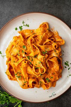 a white plate topped with pasta covered in sauce and parsley