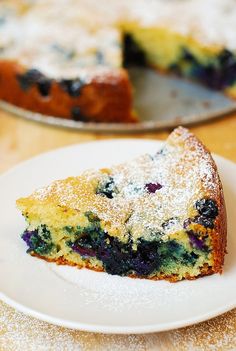 a slice of blueberry coffee cake on a white plate with powdered sugar over it