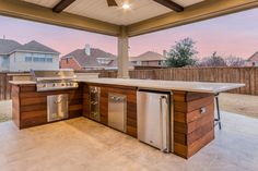 an outdoor kitchen with grill, sink and refrigerator