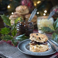 a scone with raisins and jam on a plate next to some cookies