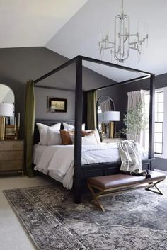 a bedroom with a canopy bed, chandelier and rugs on the floor