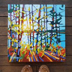 a pair of shoes sitting on top of a wooden floor next to a painting