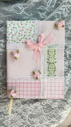 a close up of a piece of paper on a lace table cloth with flowers and ribbons