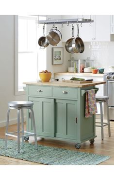 a kitchen island with two pots and pans hanging from it's hooks on the ceiling