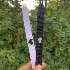 two purple and black wristbands with white flowers on them in front of some trees