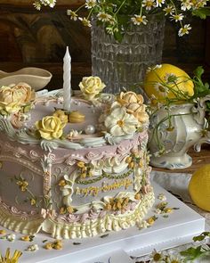 there is a cake with flowers and candles on the table in front of lemons