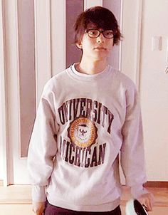 a young man holding a frisbee in his right hand and wearing a sweatshirt with the university of michigan on it