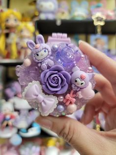 a hand holding a small purple flower with bunny decorations on it's centerpiece