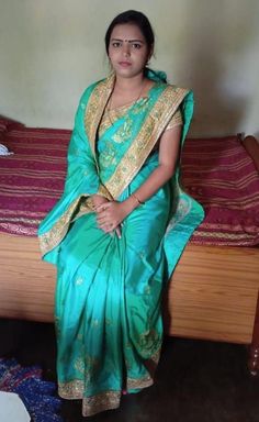 a woman in a green sari sitting on a bed