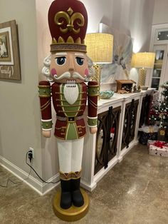 a large nutcracker standing on top of a wooden stand next to a christmas tree