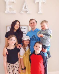 a group of people standing next to each other in front of a sign that says eat