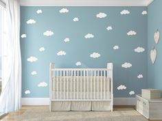 a baby's room with blue walls and white clouds on the wall