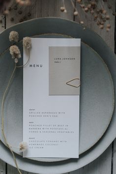 the menu card is placed on top of the plate, with dried flowers in front of it