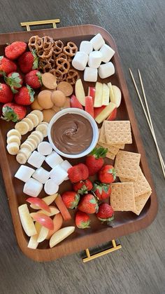 a platter filled with fruit, crackers and pretzels