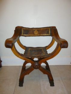 an old wooden chair sitting on top of a tile floor next to a white wall