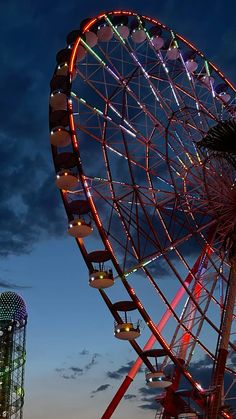 the ferris wheel is lit up at night with bright lights on it's sides