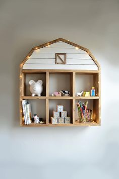 a wooden shelf filled with lots of books and other items next to a white wall