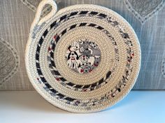 a woven basket sitting on top of a couch next to a blue pillow with black, white and red designs