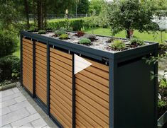 an outdoor garden with wooden slats and plants growing on the top part of it