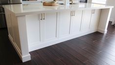 a kitchen with white cabinets and wood flooring in the center island, along with stainless steel appliances