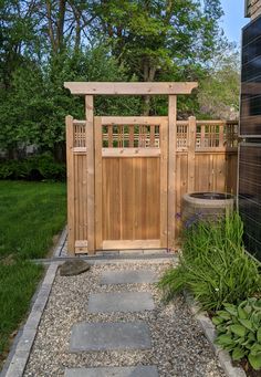 a wooden gate is in the middle of a graveled area with plants and flowers