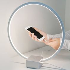 a person holding a cell phone in front of a mirror with an apple charging station