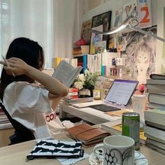 a woman sitting at a desk reading a book and holding her head in her hands