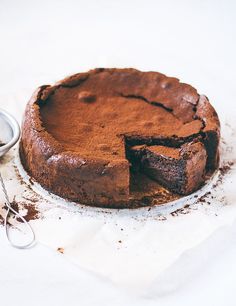 a chocolate cake sitting on top of a table next to a measuring cup and spoon