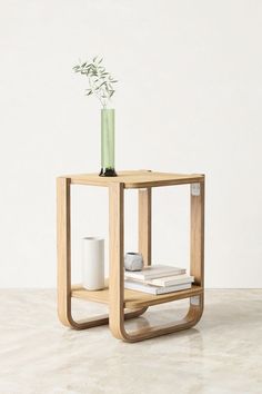 a small wooden table with a vase on top and books in the bottom shelf next to it