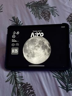 a clock with the moon on it sitting on a bed