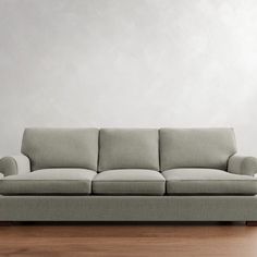 a couch sitting on top of a hard wood floor next to a white wall and wooden floors