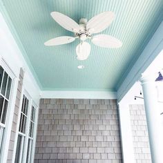 a white ceiling fan mounted to the side of a wall next to a bath tub