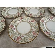 six plates with floral designs on them sitting on a counter top next to each other