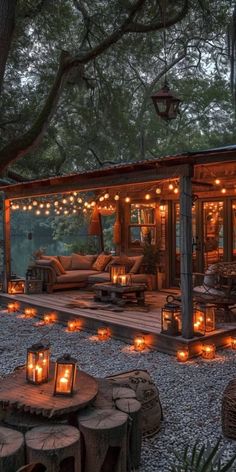 an outdoor living area with candles lit up on the ground and trees in the background