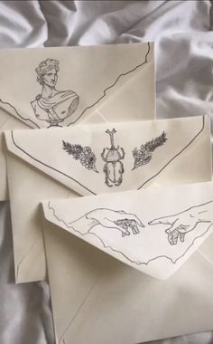 two envelopes with drawings on them sitting on a bed