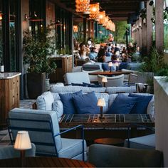 an outdoor dining area with blue and white furniture, chandeliers and potted plants