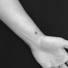 a person's left hand with a small tattoo on the middle of their wrist