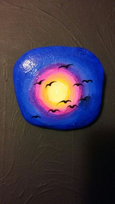 a painted rock with birds flying in the sky