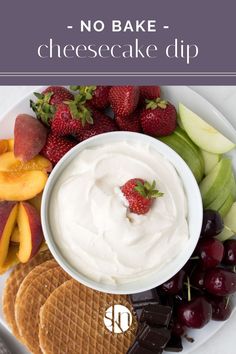 a white plate topped with fruit and crackers next to a bowl of cream cheesecake dip