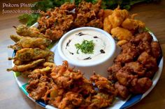 a plate full of fried food with dip in the middle and other foods on it